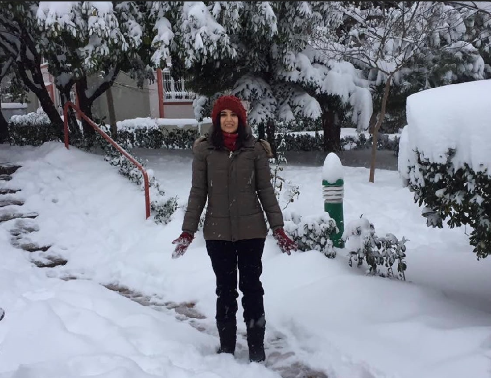 Eda Ketenci, karla kaplı bir bahçede, kışlık kıyafetleriyle karların arasında.